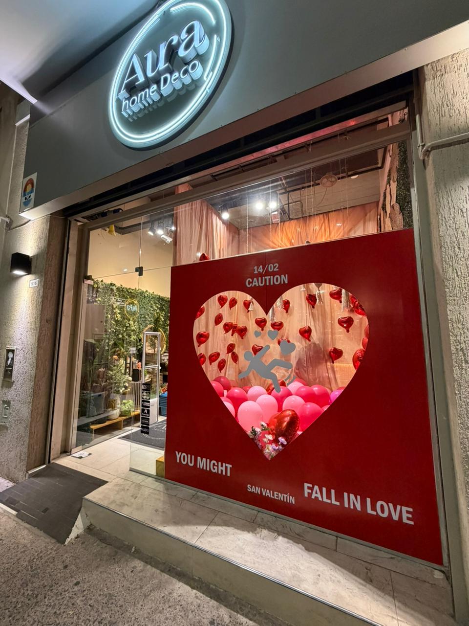 Vidriera de San Valentín vista desde la calle, con el cartel de neón de Aura Home Deco